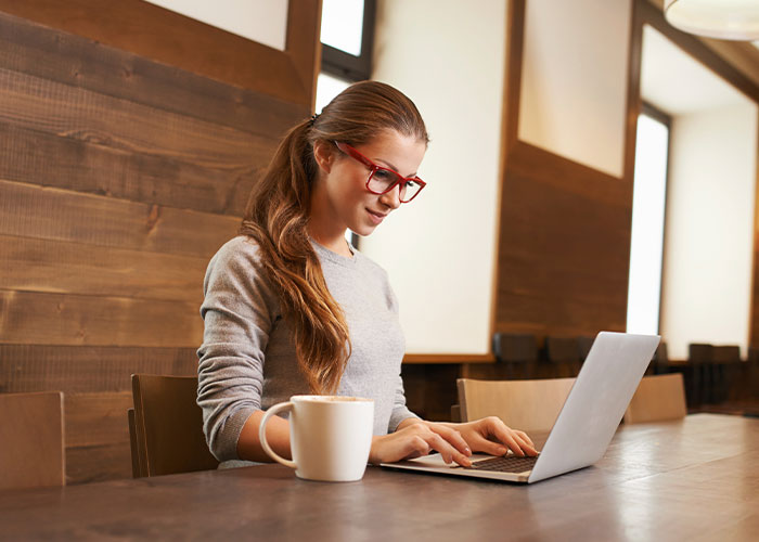 Image of woman sitting at table looking at her laptop